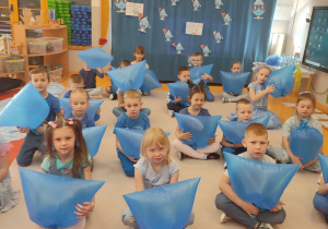 dzieci siedzą z niebieskimi workami